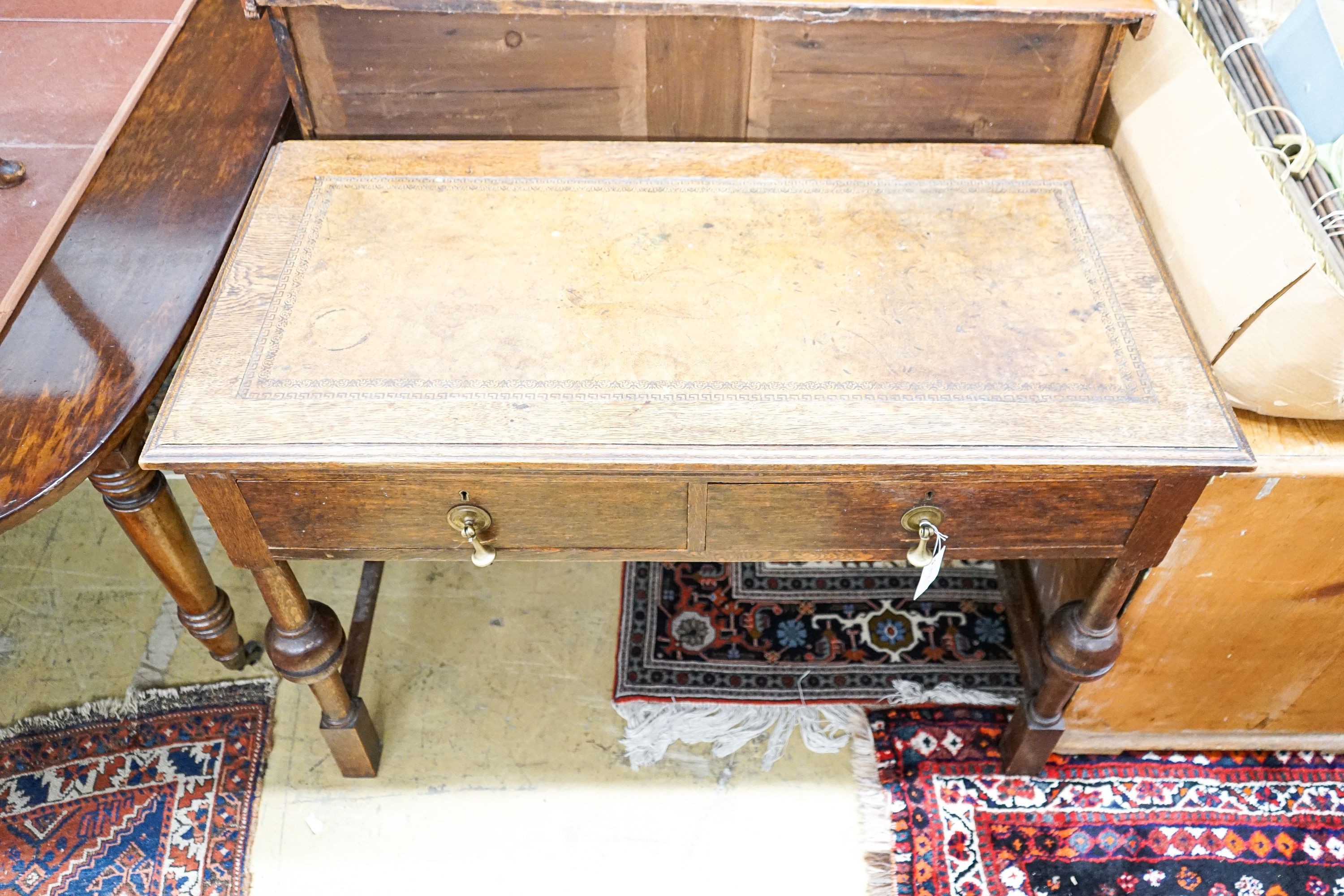 A 1920's oak two drawer writing table, with a leather inset top, length 106cm, depth 52cm, height 75cm